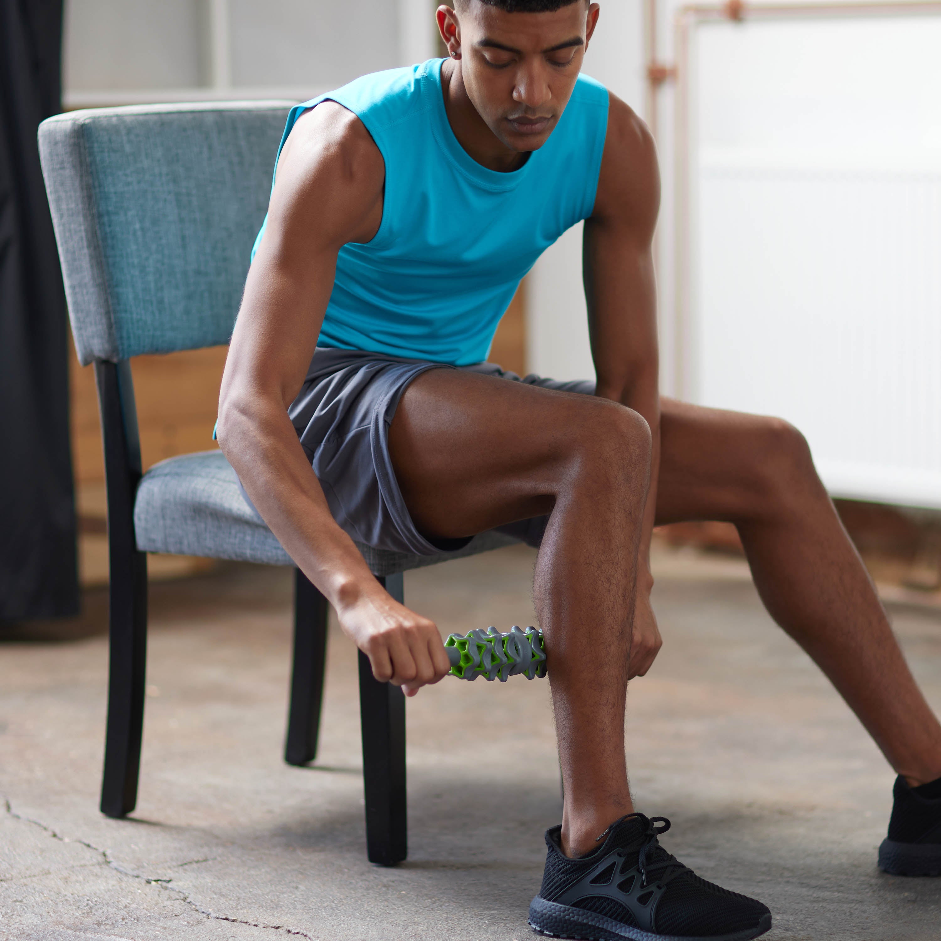 Seated person using the Restore Adjustable Massage Roller Plus in the calf